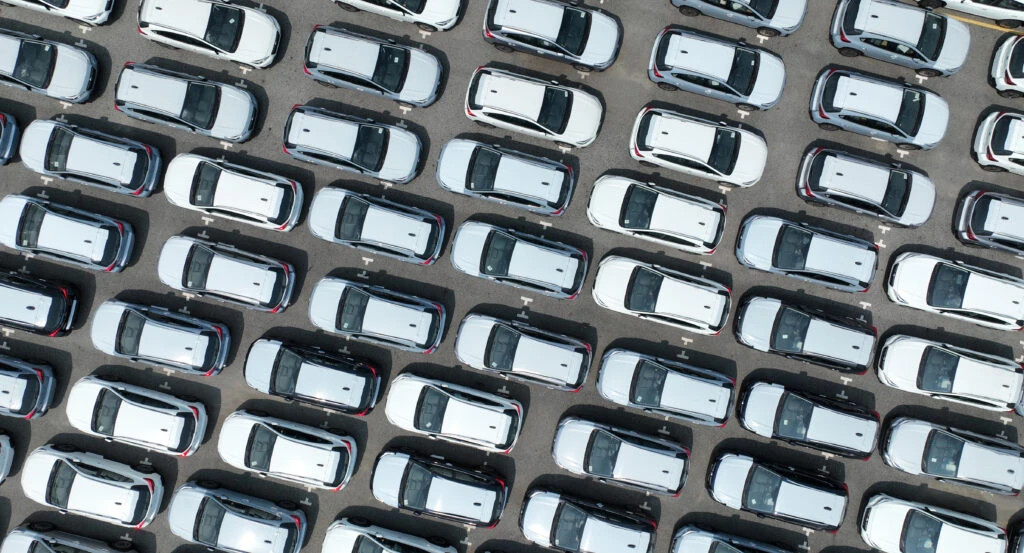 aerial view of a parking lot full of identical white cars, illustrating the baader-meinhof phenomenon, where you buy a car and start seeing it everywhere.