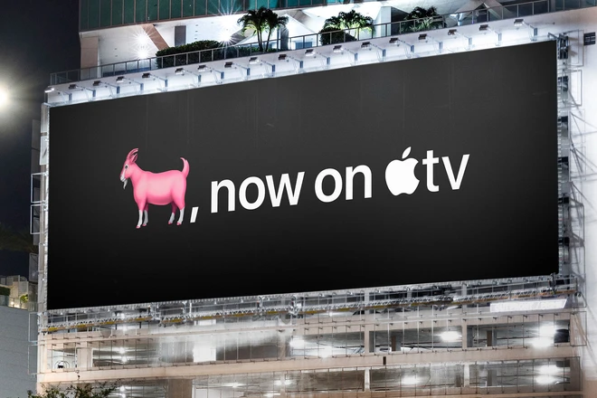 Large billboard at night advertising a pink goat emoji and 'now on Apple TV'.