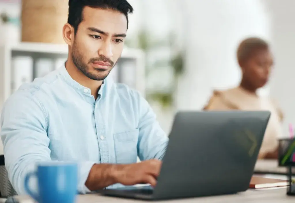 Focused man typing on a laptop in an office, researching effective on page SEO services for businesses.