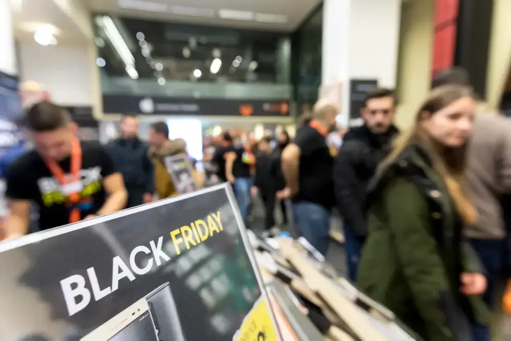Crowd of shoppers in a store with a 'Black Friday' sign in the foreground, demonstrating scarcity marketing.