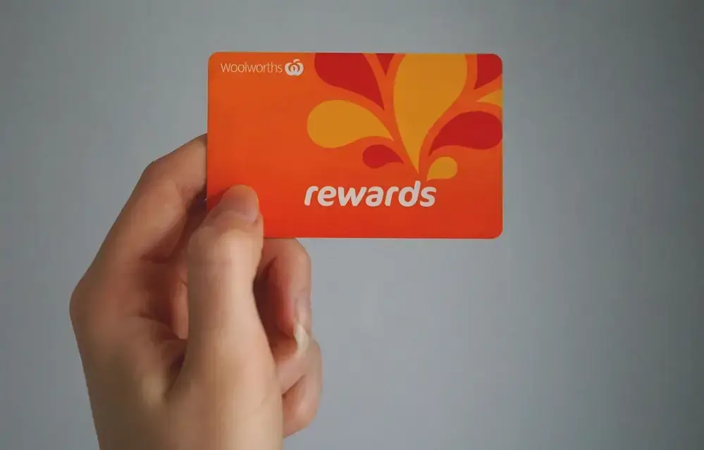 Hand holding an orange Woolworths Rewards card, a key strategy to increase customer lifetime value through loyalty programs.