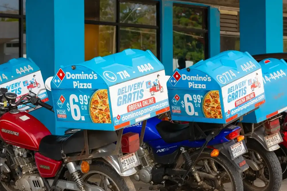 Domino's Pizza delivery motorcycles with blue boxes showing a $6.99 pizza deal, illustrating the psychology of pricing.