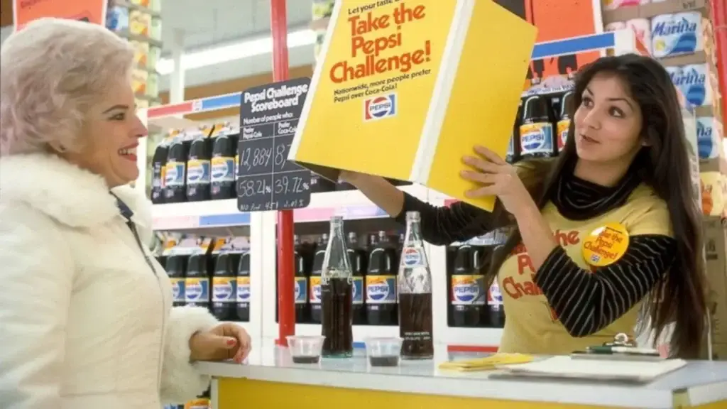 A woman in a white coat smiles at a Pepsi Challenge promoter, who holds a 'Take the Pepsi Challenge!' sign. This historical marketing campaign highlights the impact of conversion rate optimization.
