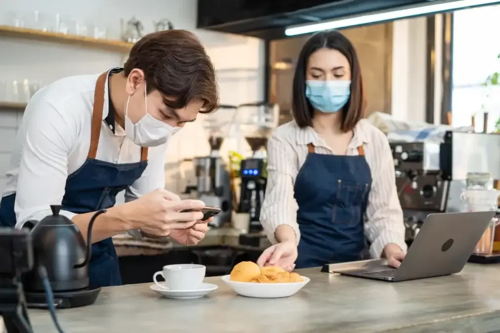 Barista checking digital marketing analytics on smartphone to understand what CPA is in café setting.