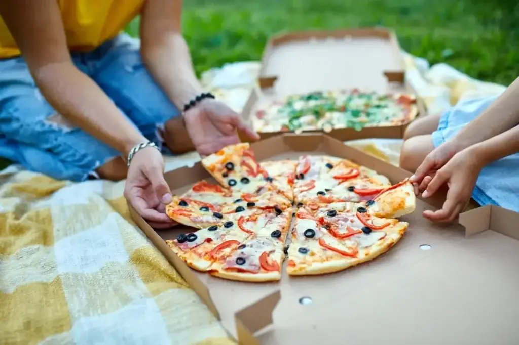 Two people sharing a pizza on a checkered blanket, illustrating collaborative fractional leadership.