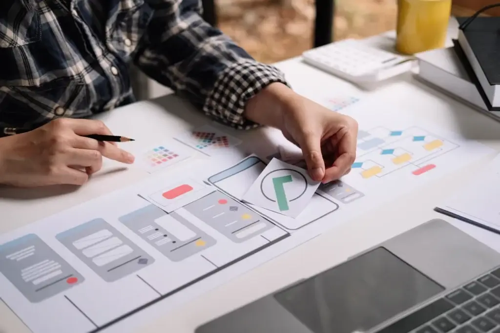 Designer creating a user interface with wireframes and color swatches, illustrating the primacy effect in design.